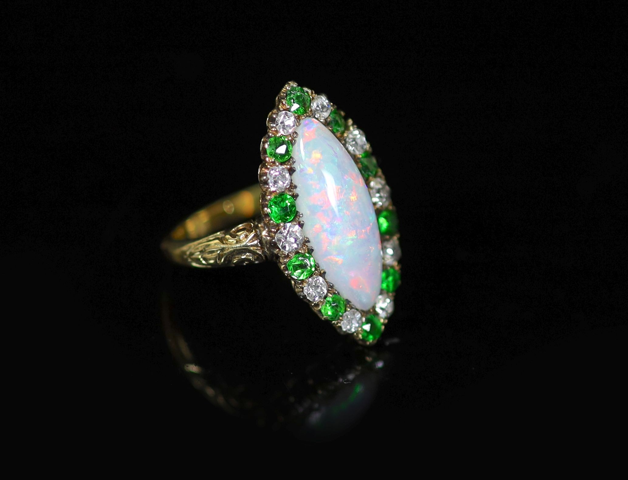 An early 20th century 18ct gold, white opal, green garnet and diamond set navette shaped dress ring